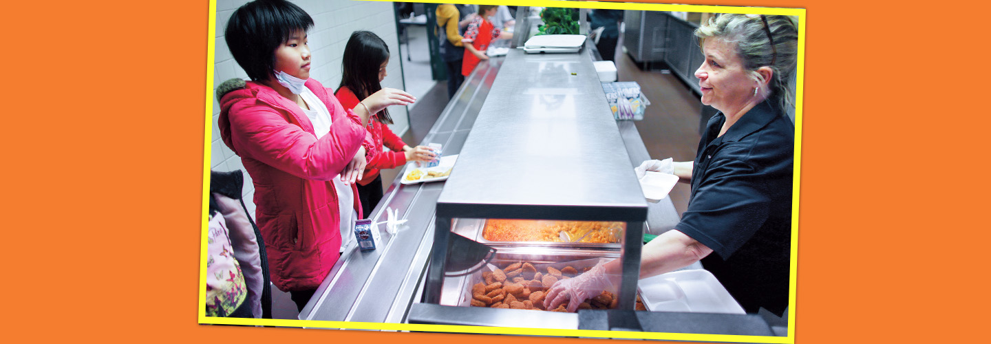 Photo of a student signing what they want for lunch to the cafeteria worker