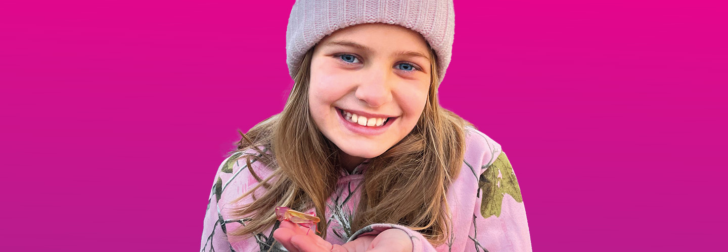 Image of a young person smiling & holding an insect in their hand