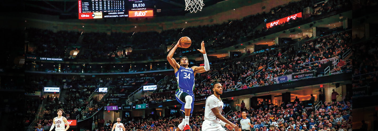 Image of basketball players playing in a large, crowded stadium